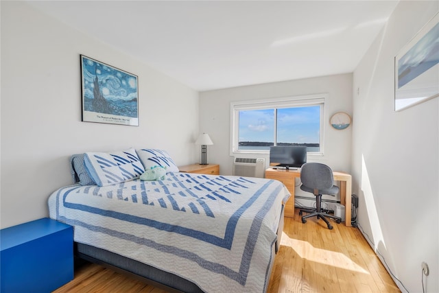 bedroom featuring a wall mounted AC and wood finished floors