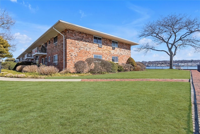 view of side of property with a yard, brick siding, and a water view