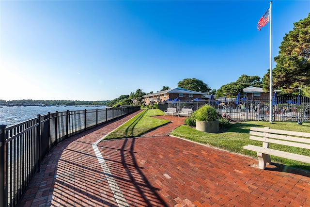 view of property's community with a water view, fence, and a lawn