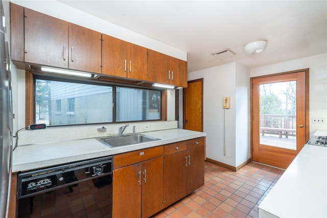 kitchen with light countertops, black dishwasher, light tile patterned flooring, and a sink