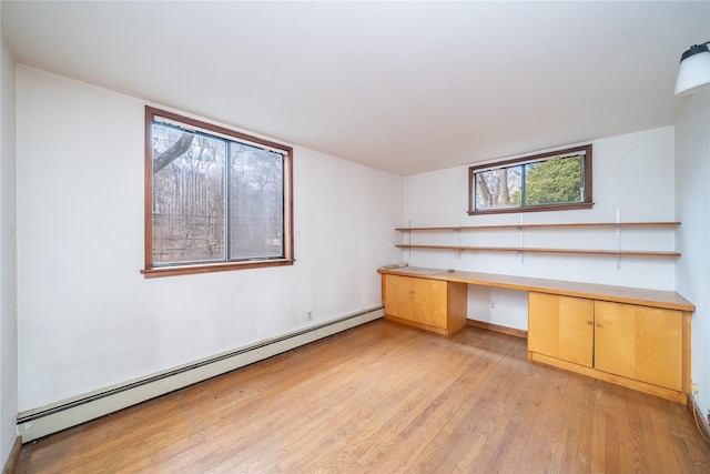 unfurnished office featuring a baseboard heating unit, light wood-style flooring, and built in study area