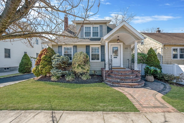 view of front of house featuring a chimney, fence, and a front lawn