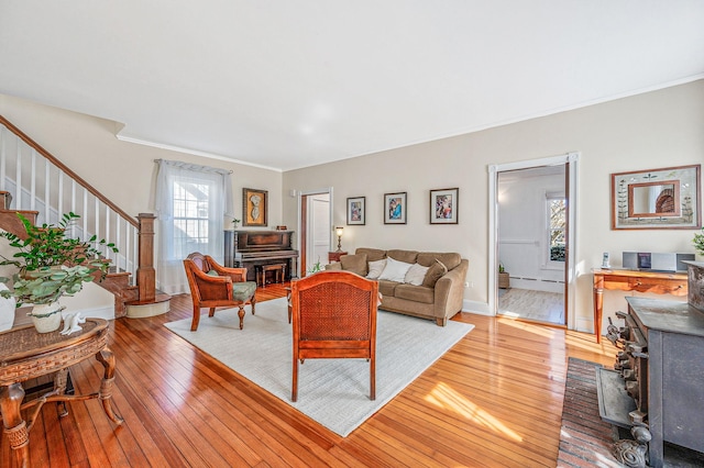 living room with crown molding, light wood-type flooring, a fireplace, and stairs