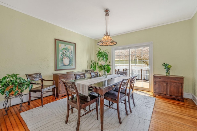 dining room featuring ornamental molding, baseboard heating, baseboards, and light wood finished floors