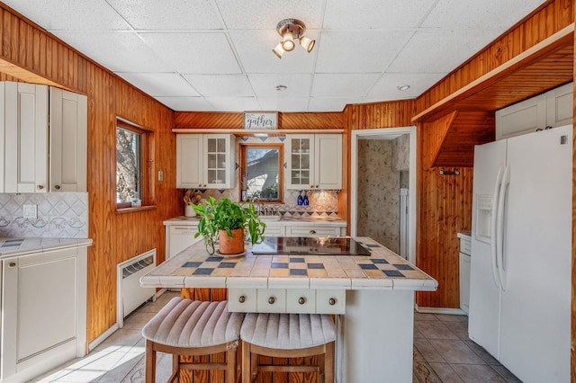 kitchen featuring tile counters, white appliances, and wooden walls