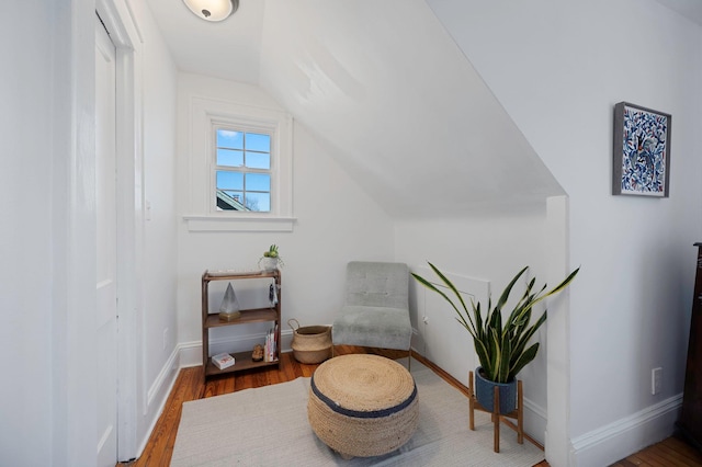 sitting room featuring baseboards, vaulted ceiling, and wood finished floors