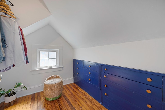 interior space with vaulted ceiling, baseboards, and wood finished floors