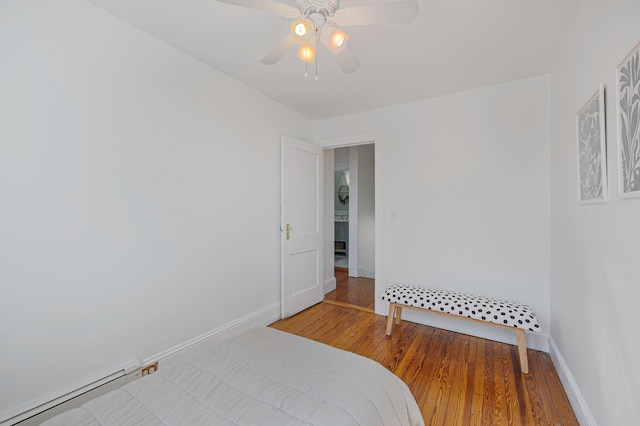 bedroom featuring a ceiling fan, baseboards, baseboard heating, and wood finished floors