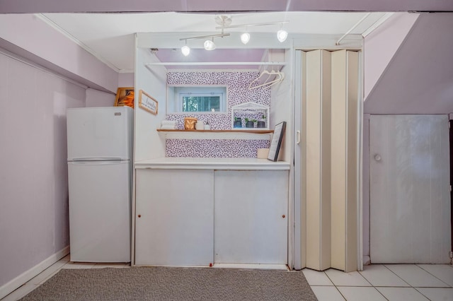 kitchen featuring light tile patterned floors, ornamental molding, freestanding refrigerator, and white cabinetry