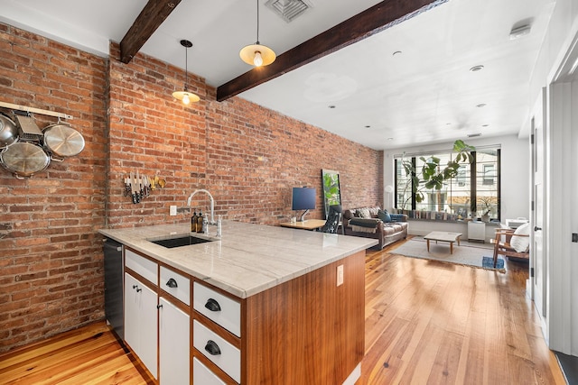 kitchen featuring light wood finished floors, brick wall, beam ceiling, and a sink