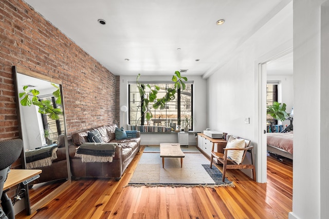 living area with brick wall and hardwood / wood-style flooring