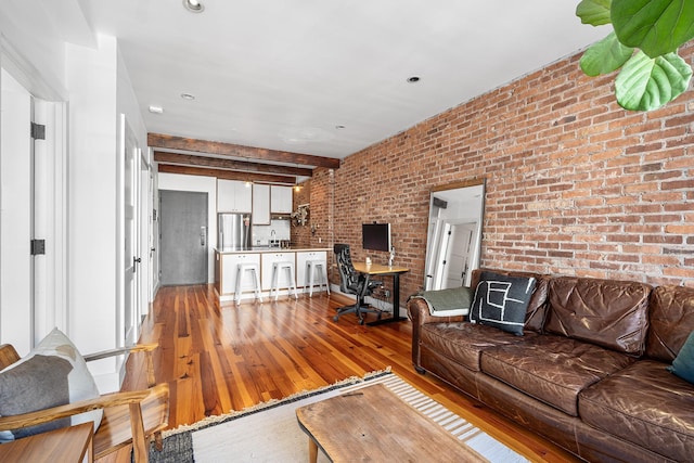 living room with brick wall, beam ceiling, and light wood-style flooring