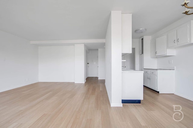 33-65 14th St Unit 5D, Astoria, NY 11106 - kitchen with baseboards, open floor plan, light countertops, white cabinetry, and light wood-style flooring