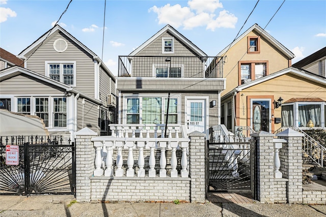 view of front of home with a fenced front yard, a balcony, and a gate