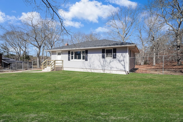 rear view of property with roof with shingles, fence, and a yard