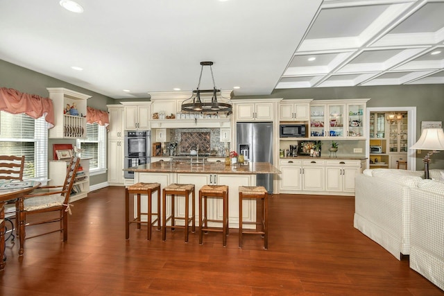 kitchen featuring tasteful backsplash, coffered ceiling, glass insert cabinets, appliances with stainless steel finishes, and dark wood-style flooring