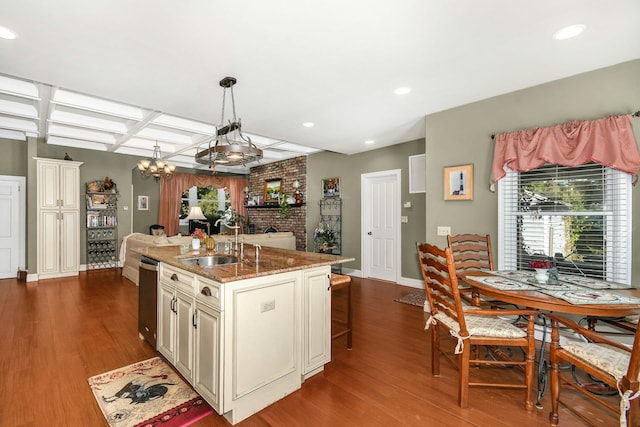 kitchen with stone counters, coffered ceiling, a sink, cream cabinetry, and dark wood-style floors