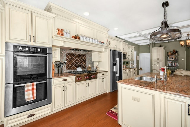 kitchen with cream cabinets, stainless steel appliances, dark wood-style flooring, a sink, and decorative backsplash