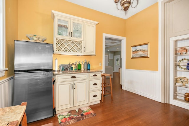 kitchen with a wainscoted wall, dark wood-style flooring, and freestanding refrigerator