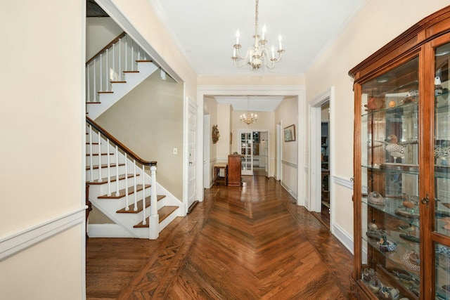 foyer with parquet flooring, an inviting chandelier, ornamental molding, baseboards, and stairs