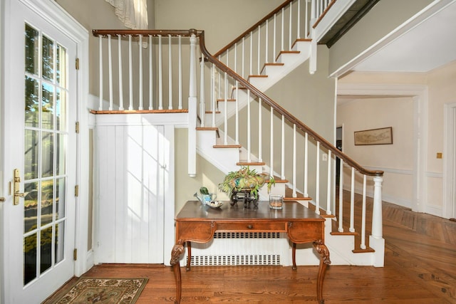 foyer entrance featuring radiator, parquet floors, and stairway