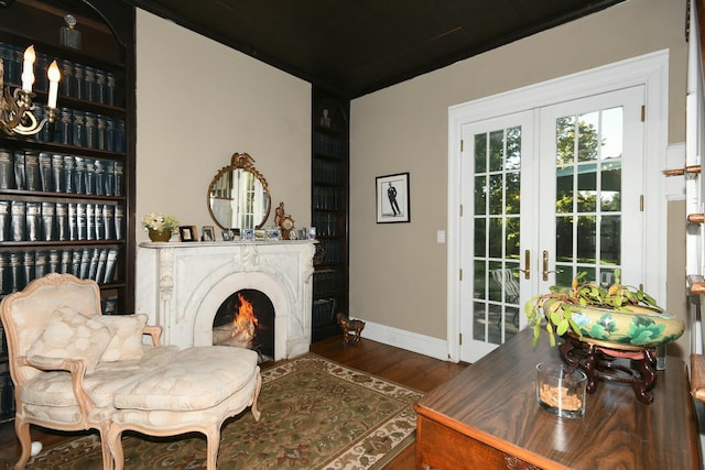 sitting room featuring french doors, a fireplace, wood finished floors, and baseboards