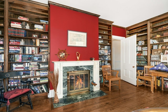 living area with wood finished floors, wall of books, and a premium fireplace