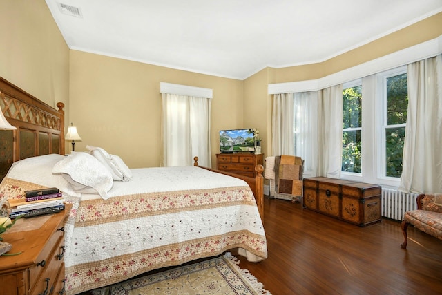 bedroom with ornamental molding, radiator, visible vents, and dark wood-style flooring