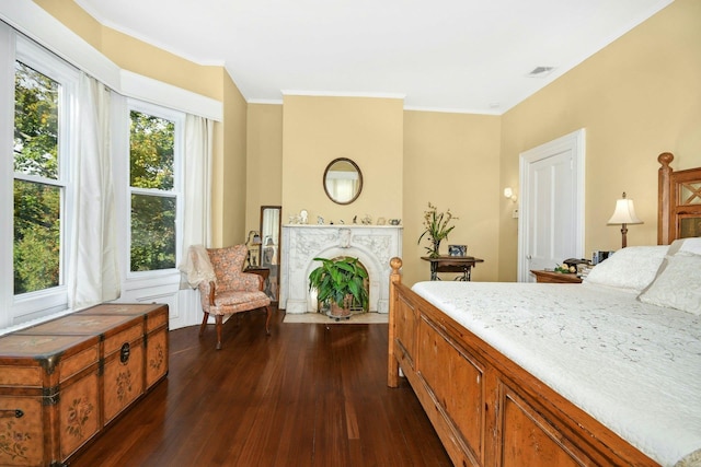 bedroom featuring crown molding, a fireplace, visible vents, and dark wood-style flooring