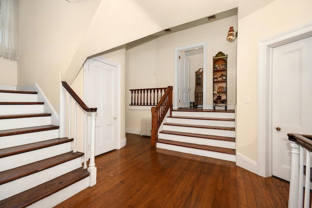 stairway with baseboards, radiator heating unit, and hardwood / wood-style flooring