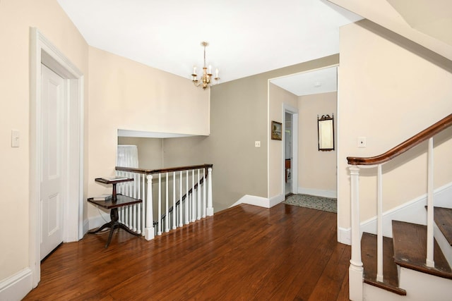 interior space featuring wood-type flooring, baseboards, a chandelier, and an upstairs landing