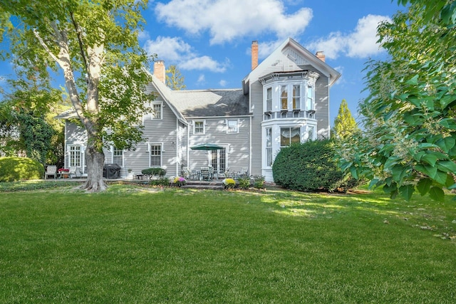 back of house featuring a yard and a chimney