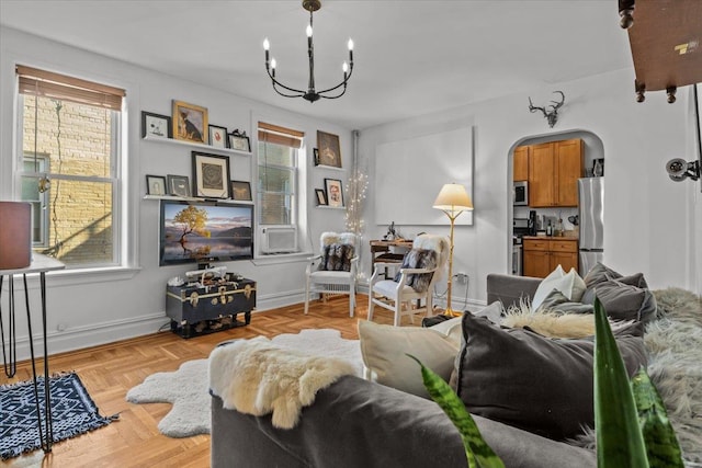 living room featuring arched walkways, a chandelier, and baseboards