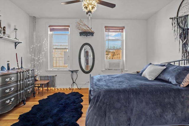 bedroom featuring radiator, multiple windows, cooling unit, and wood finished floors