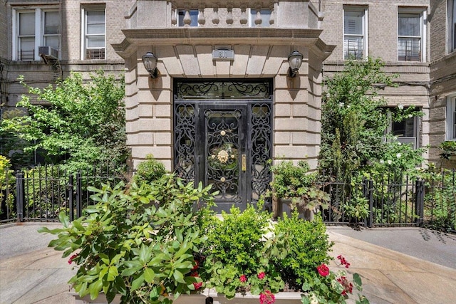 view of exterior entry featuring brick siding and fence