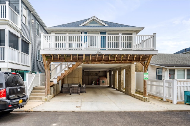 view of front facade featuring roof with shingles, a porch, a carport, driveway, and stairs