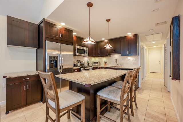 kitchen with visible vents, backsplash, stainless steel appliances, a kitchen bar, and a sink