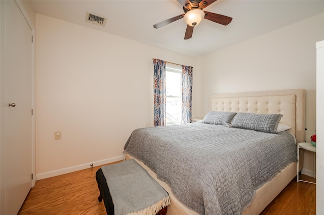 bedroom featuring a ceiling fan, wood finished floors, visible vents, and baseboards