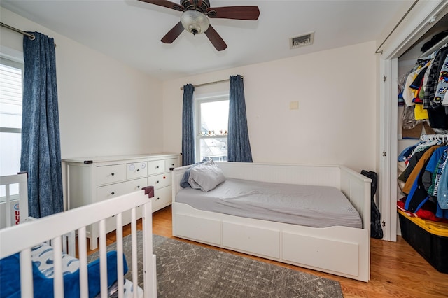 bedroom with a ceiling fan, visible vents, and wood finished floors