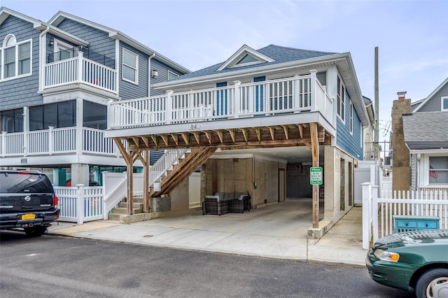 view of front of house featuring a shingled roof, stairs, fence, and a carport