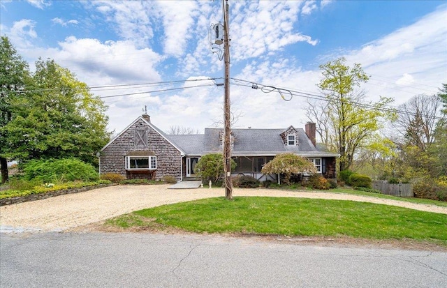 view of front of house featuring curved driveway, a chimney, and a front lawn