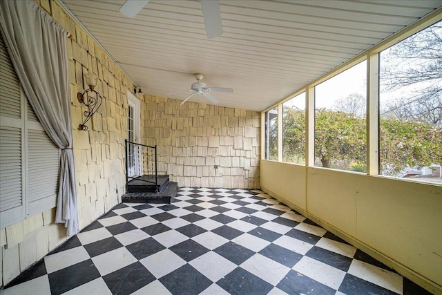 unfurnished sunroom featuring ceiling fan and a wealth of natural light