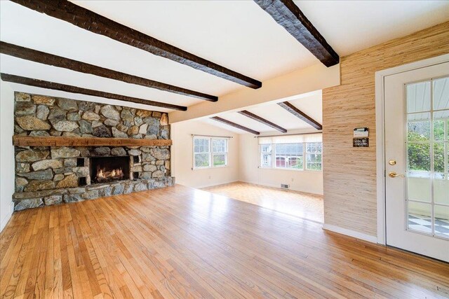 unfurnished living room with lofted ceiling with beams, a fireplace, hardwood / wood-style floors, and visible vents