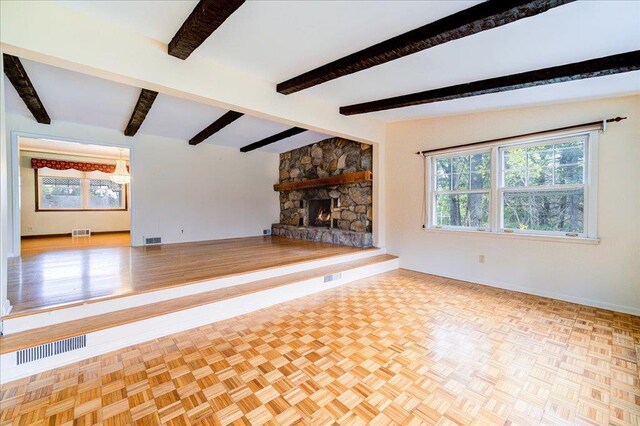 unfurnished living room featuring a healthy amount of sunlight, baseboards, a stone fireplace, and visible vents