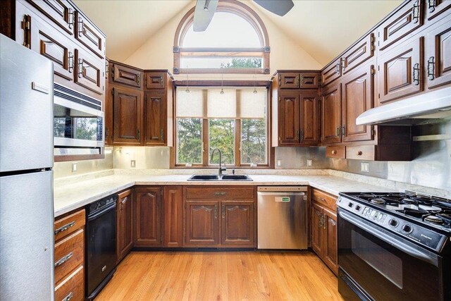 kitchen with lofted ceiling, a healthy amount of sunlight, light countertops, a sink, and appliances with stainless steel finishes