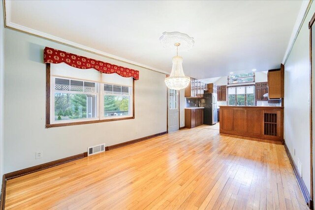 kitchen with visible vents, freestanding refrigerator, a notable chandelier, and ornamental molding