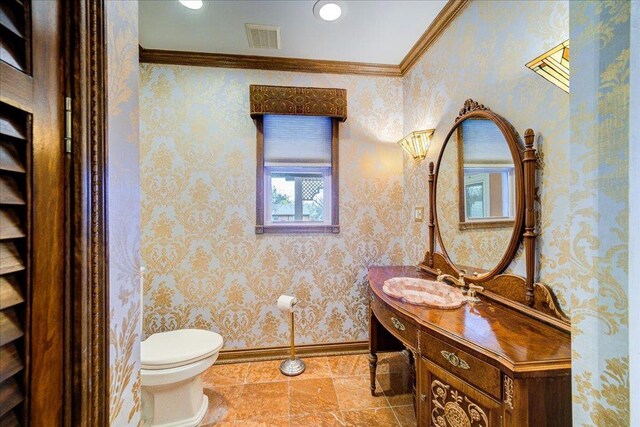 half bathroom featuring crown molding, vanity, toilet, baseboards, and visible vents