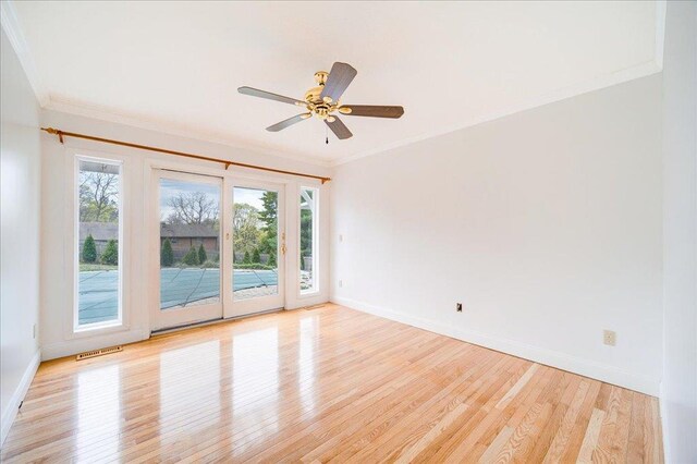 spare room featuring crown molding, baseboards, and light wood-type flooring