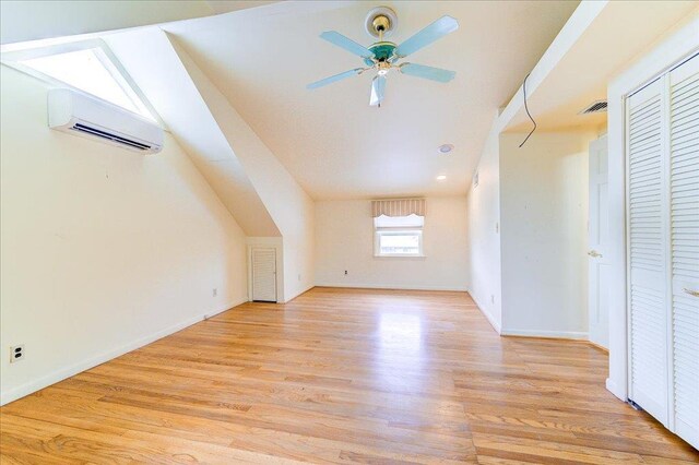 bonus room with light wood-style floors, a ceiling fan, a wall mounted air conditioner, and visible vents