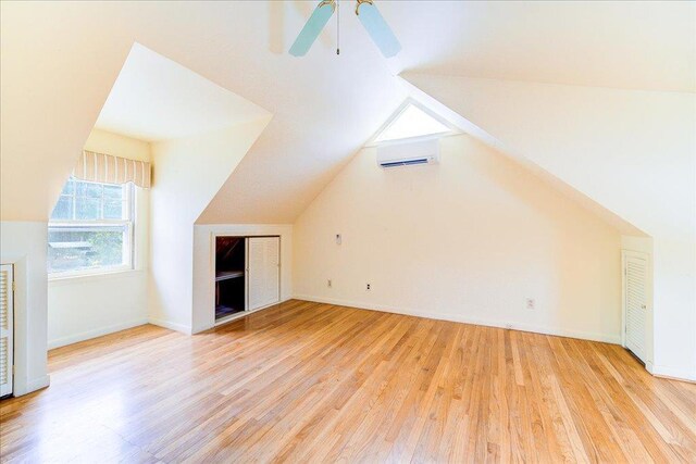 bonus room with light wood-style floors, vaulted ceiling, and a wall mounted air conditioner